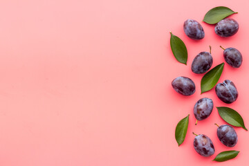 Purple plums with leaves top view. Food fruits background