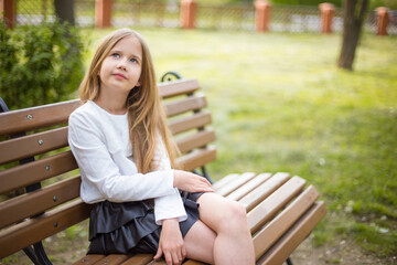 beautiful girl in a white blouse thinking about something on a bench