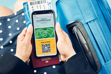 Digital covid certificate. Covid vaccination digital pass. Woman passenger holding digital medical pass on her mobile phone, passport and airplane ticket. Traveler showing digital covid test result