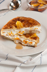 top, front view, close up of, orange, cream, French toast sandwich, stuffed with orange, cream composting drizzled with maple syrup, on round, white plate