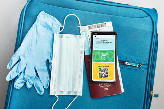 Digital covid certificate. Vaccination digital pass. Digital medical pass, passport, airplane ticket and face mask on travel bag. Digital covid vaccination pass on mobile as medical pass for travel