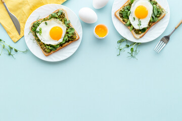 Breakfast with toasts of fried eggs and avocado saurce. Top view