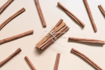 Top view of cinnamon sticks bunch tied with a rope on brown background. Minimal. Flat layout.