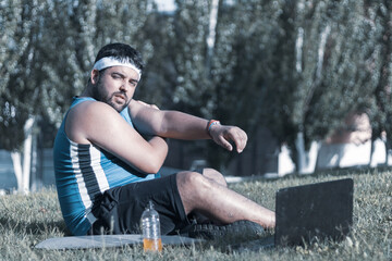 
a fat boy stretching his arms while sitting on a grass.
willpower.
positivism concept.