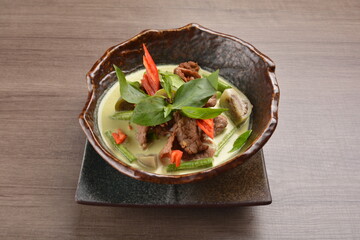 thai green curry hot spicy soup with beef or chicken with vegetables on wood background asian halal...