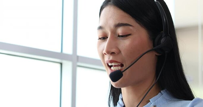 Asian woman operator and team working with headsets and desktop computer at telemarketing customer service