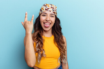 Young mexican woman isolated on blue background showing rock gesture with fingers