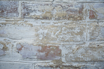White painted old brick wall with red cracked bricks.