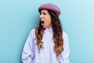 Young mexican woman isolated on blue background shouting very angry, rage concept, frustrated.