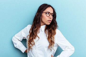 Young mexican woman isolated on blue background looks aside smiling, cheerful and pleasant.