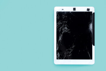 cracked or broken screen of smartphone or tablet temporarily fixed with black tape on green pastel background, isolated object with clipping path