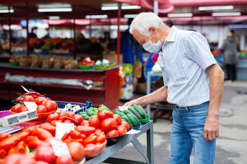 retired european man wearing medical mask protecting against virus buying tomatoes in market