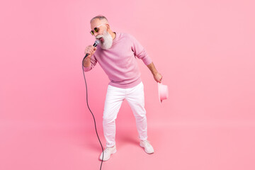 Full body photo of trendy grey hair mature man sing wear eyewear cap sweater isolated on pink background