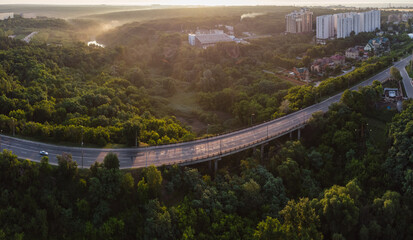 Aerial sunrise morning panorama Derevianka street bridge across Sarzhyn Yar in Kharkiv city. Buildings with lots of greenery in fog at dawn in nice light. Drone view on Sokilnyky.