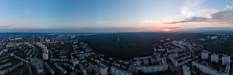 Obraz premium Aerial sunrise panorama wide view Kharkiv city Pavlove Pole district. Multistory buildings near forest with telecommunication tower and scenic early morning dawn sky