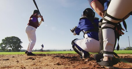 Diverse group of female baseball players playing on the field, hitter hitting pitched ball - Powered by Adobe