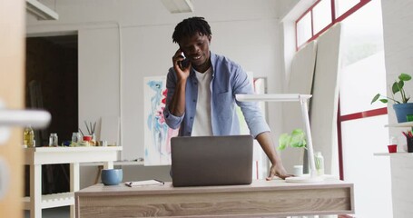 African american male artist talking on smartphone at art studio