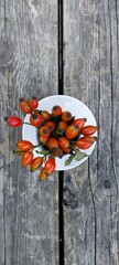 Rose hips red in a white ceramic pair on a wooden table. Place for your text.