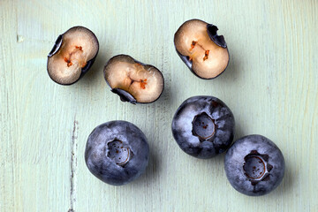 Several blueberries in a cut on a wooden blue background