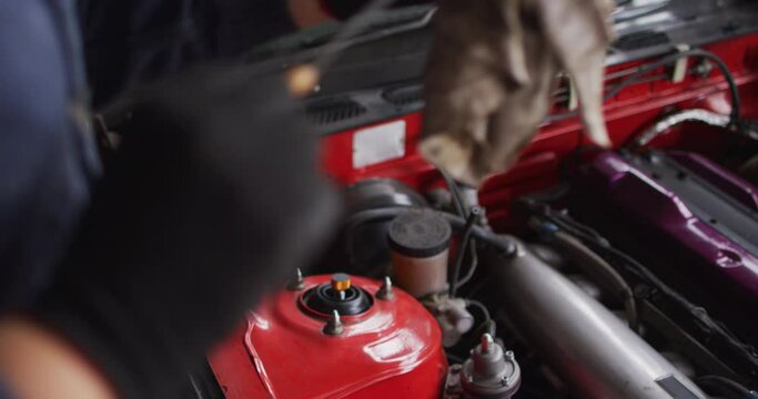 Mid section of female mechanic cleaning equipment of the car with a cloth at a car service station