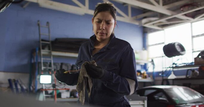 Female mechanic cleaning equipment of the car with a cloth at a car service station