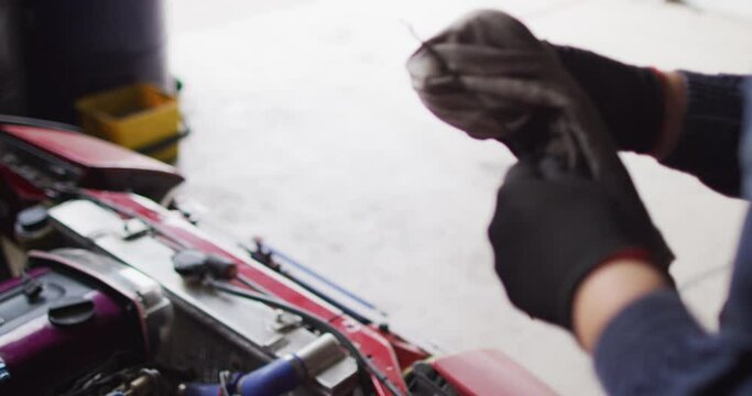 Mid section of female mechanic cleaning equipment of the car with a cloth at a car service station