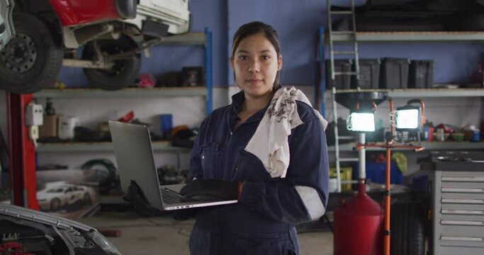 Portrait of female mechanic using laptop and smiling at a car service station