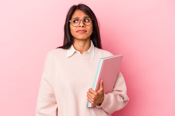Young student latin woman isolated on pink background confused, feels doubtful and unsure.