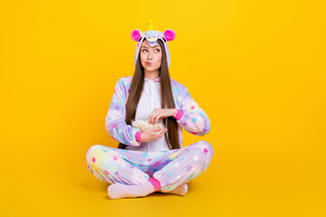 Portrait of attractive minded suspicious girl sitting lotus pose eating corn thinking isolated over...