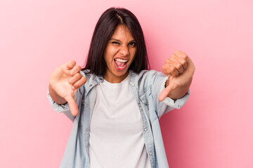 Young latin woman isolated on pink background showing thumb down and expressing dislike.