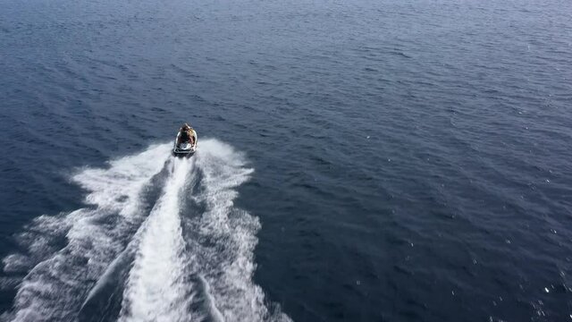 Aerial drone tracking footage of jet ski speeding over the sea. Super fast travel, leisure summer holidays activities, water transportation.