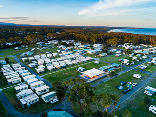 Coastal holiday caravan park at dusk with rows of cabins for accommodation and camping sites