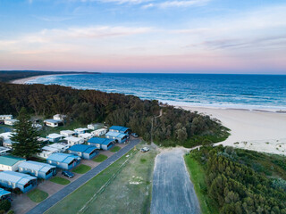 Coastal holiday caravan park with cabins and path to beach at dusk