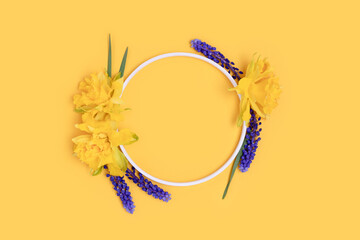 Obraz premium Wreath made of narcissus and muscari flowers on a yellow background.