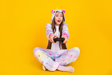 Portrait of attractive cheerful girl wearing cozy kingurumi playing game competition isolated over bright yellow color background