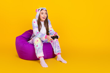 Full length body size photo girl in pajama looking copyspace playing game isolated bright yellow color background