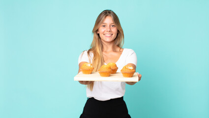 pretty young blonde woman holding a muffins tray