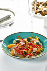 Fish fillet ceviche, fresh-marinated fish in citrus juice with fresh vegetables and orange slices, marinated sea bass