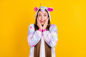 Photo portrait female teenager funny pajama surprised touching cheeks isolated vibrant yellow background
