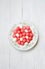 Watermelon salad with mozzarella cheese on white vintage plate. Caprese salad with watermelon balls on white wooden background.. Top view flat lay.