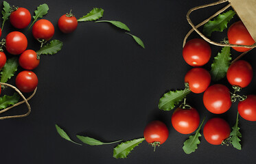 Frame made of red tomatoes and herbs on the black background. Two paper bags with fresh red tomatoes and herbs on the black background. Top view. Paper bag with fresh vegetables. Space for text.