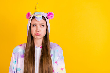 Photo of unhappy upset young woman look empty space wear pajama isolated on yellow color background