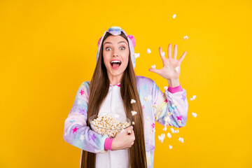 Photo portrait female teenager funny pajama keeping glass bowl throwing pop corn isolated vibrant...