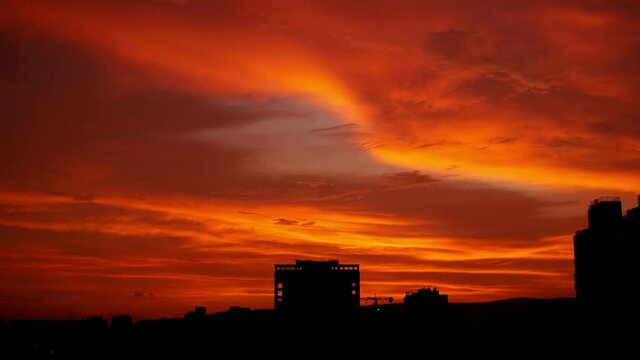 Colorful Sunset Skyline Timelapse Over Silhouette City At Dusk With Dramatic Orange Red Yellow Sky And Clouds Moving Over City.