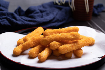 Chicken nuggets sticks in a cup on black background.
