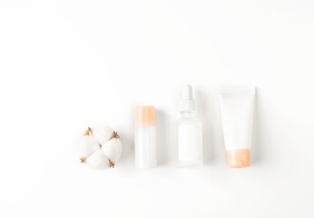 Beautiful spa composition of natural cosmetics mockup bottles with cotton flowers on white background. Top view. Flat lay style. Copy space.