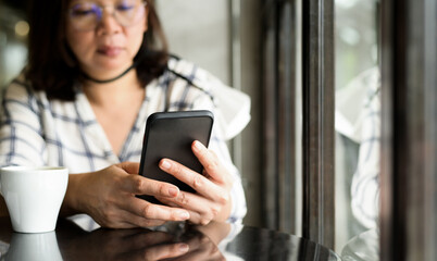 Asian woman using smartphone in coffee shop.