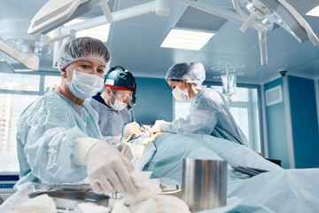 cosmetic liposuction surgery in actual operating room setting showing surgeons group during...