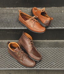 Mens leather boots and moccasins on steps. These high fashion footwear accessories are brown and mainly for fall.