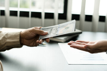 businessman giving money, dollar currency, to his partner in office - loan, payment and bribery...